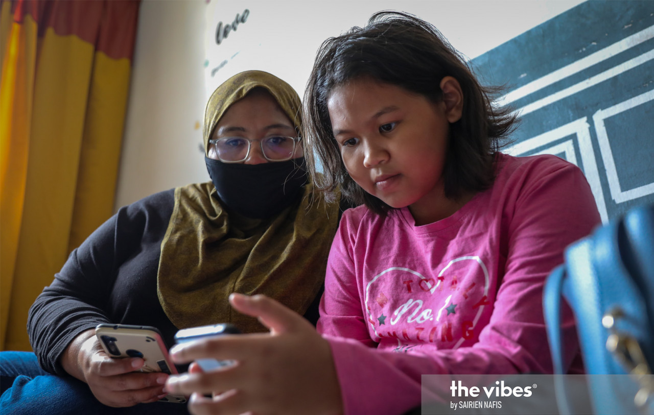 Nur Alya Aqillah Zamzuri getting her mother's help to use her handphone for her online lessons. – The Vibes pic, January 23, 2021