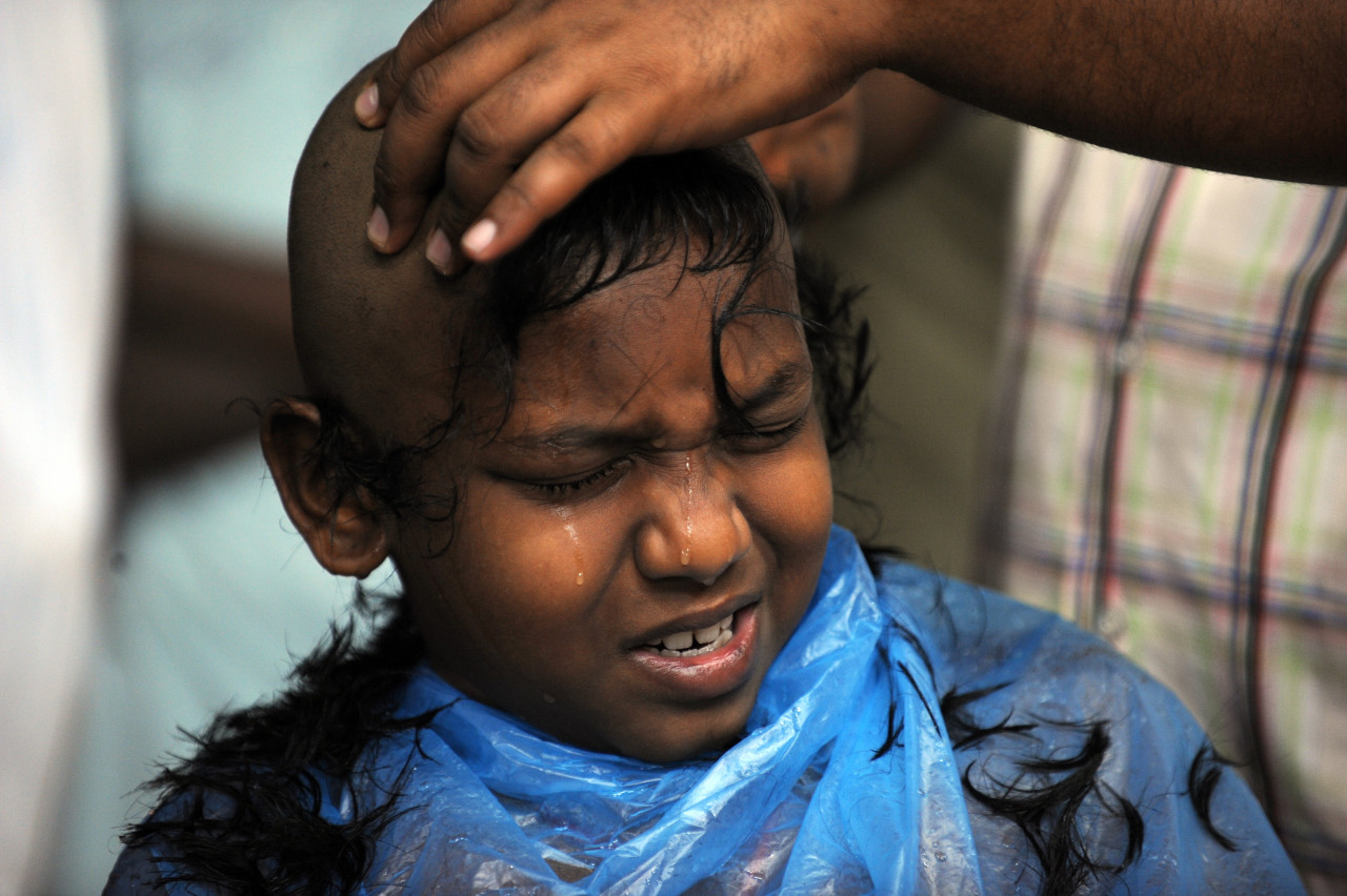 A Hindu boy cries while having his hair shaved at sunrise during Thaipusam in Batu Caves, Kuala Lumpur in 2009. – AFP pic
