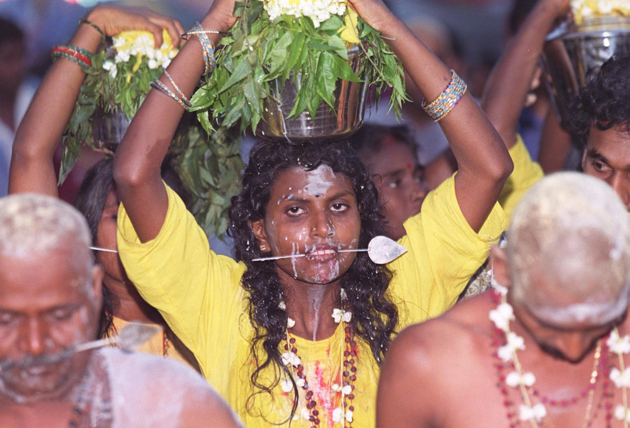 A female devotee with speared cheeks and offerings on her head walks toward the Sri Subramania Swami Temple in Batu Caves on February 10, 1998. – AFP pic