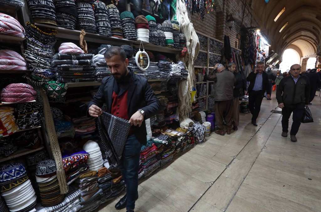 An Iraqi man folds a scarf at his shop in the old bazaar in Arbil. – AFP pic