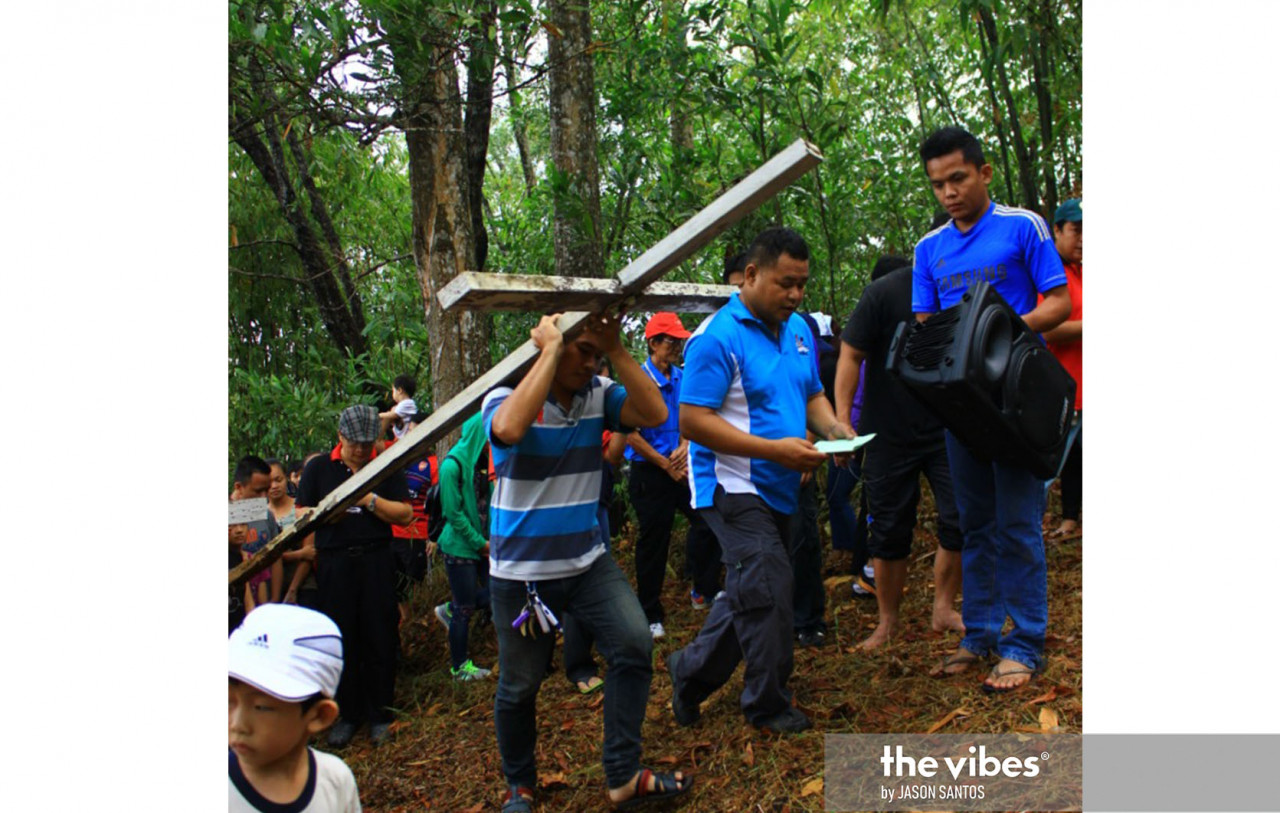 A man carrying a wooden cross on Good Friday during a Station of the Cross prayers in Sugud, Penampang. – JASON SANTOS/The Vibes pic