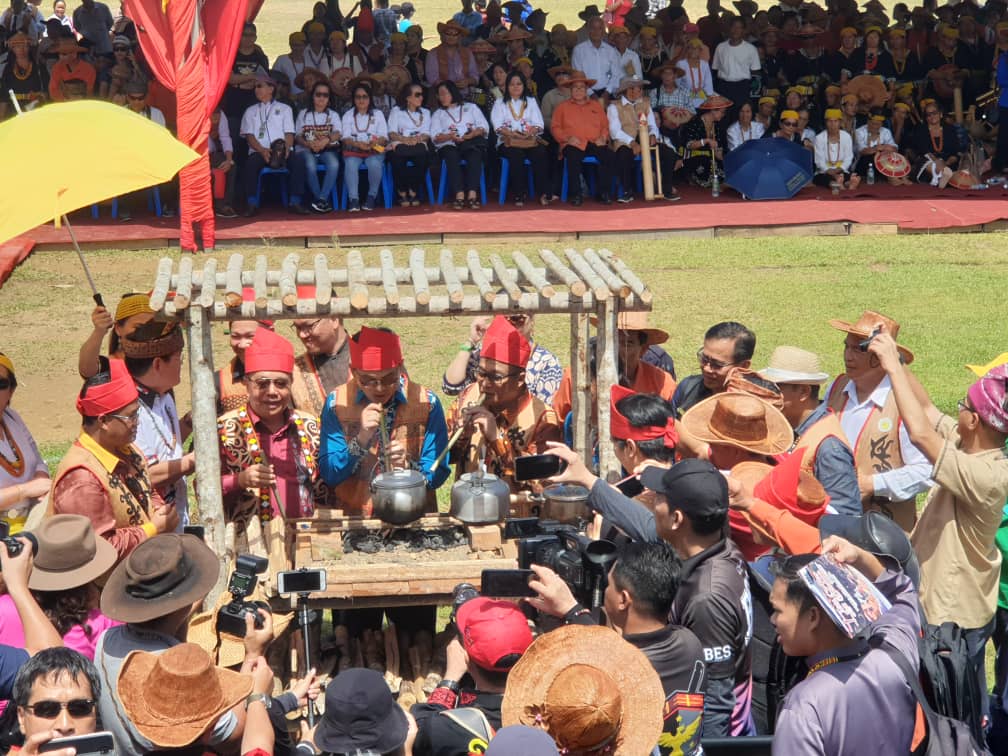 Baru (middle) blows through a bamboo pipe to spark a fire in the ambers of the stove to officially start off Irau Aco Lun Bawang. - Pic by Freddie Acho Bian