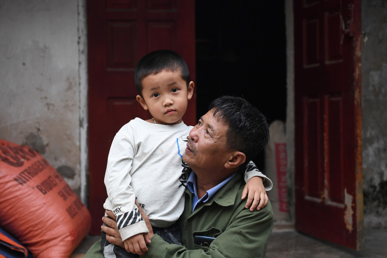 This photograph taken on October 10, 2020 shows Le Minh Tuan, father of the late 30-year-old Le Van Ha who was among 39 people found dead in a truck in Britain last year, holding Ha's son in their house in Vietnam's Nghe An province. – AFP pic, October 12, 2020