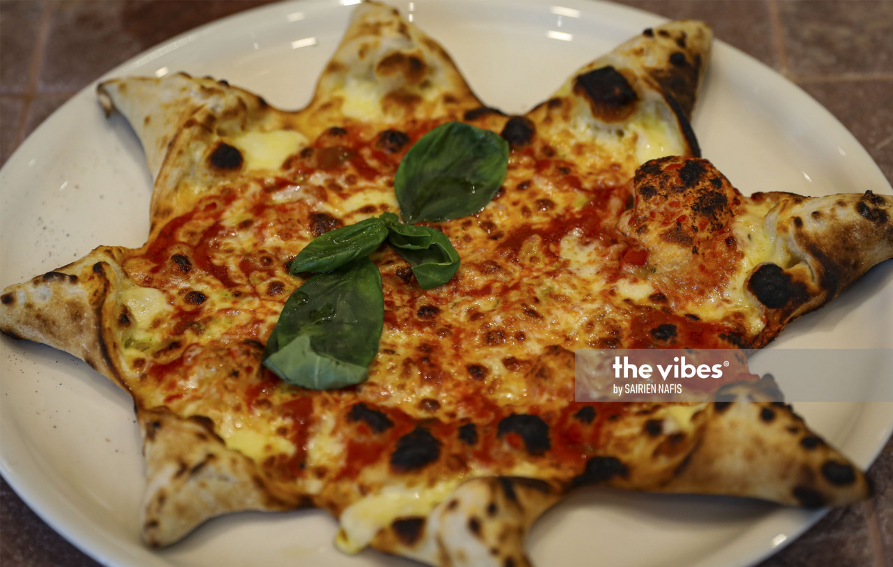 The Margherita pizza, in the shape of a Christmas star that would top a tree during this season. Topped with nothing but some basil, this pizza exemplifies the notion that the best pizza is a simple pizza. – The Vibes pic
