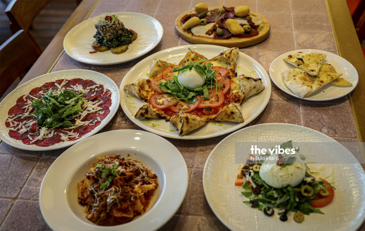 A selection of entrees and appetizers around a special Margherita pie. - The Vibes pic