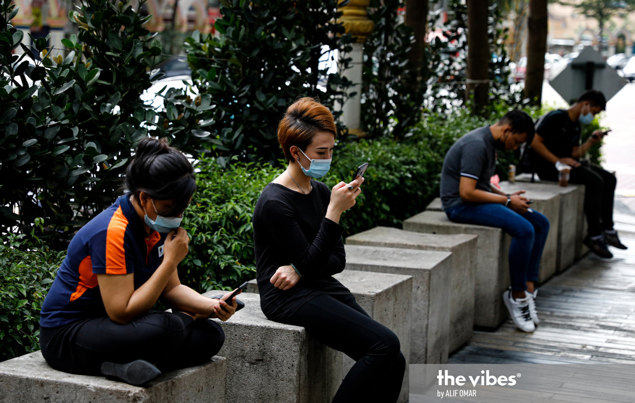 People checking their mobile phones outside a shopping complex in Kuala Lumpur on Monday. – ALIF OMAR/The Vibes pic, January 17, 2021