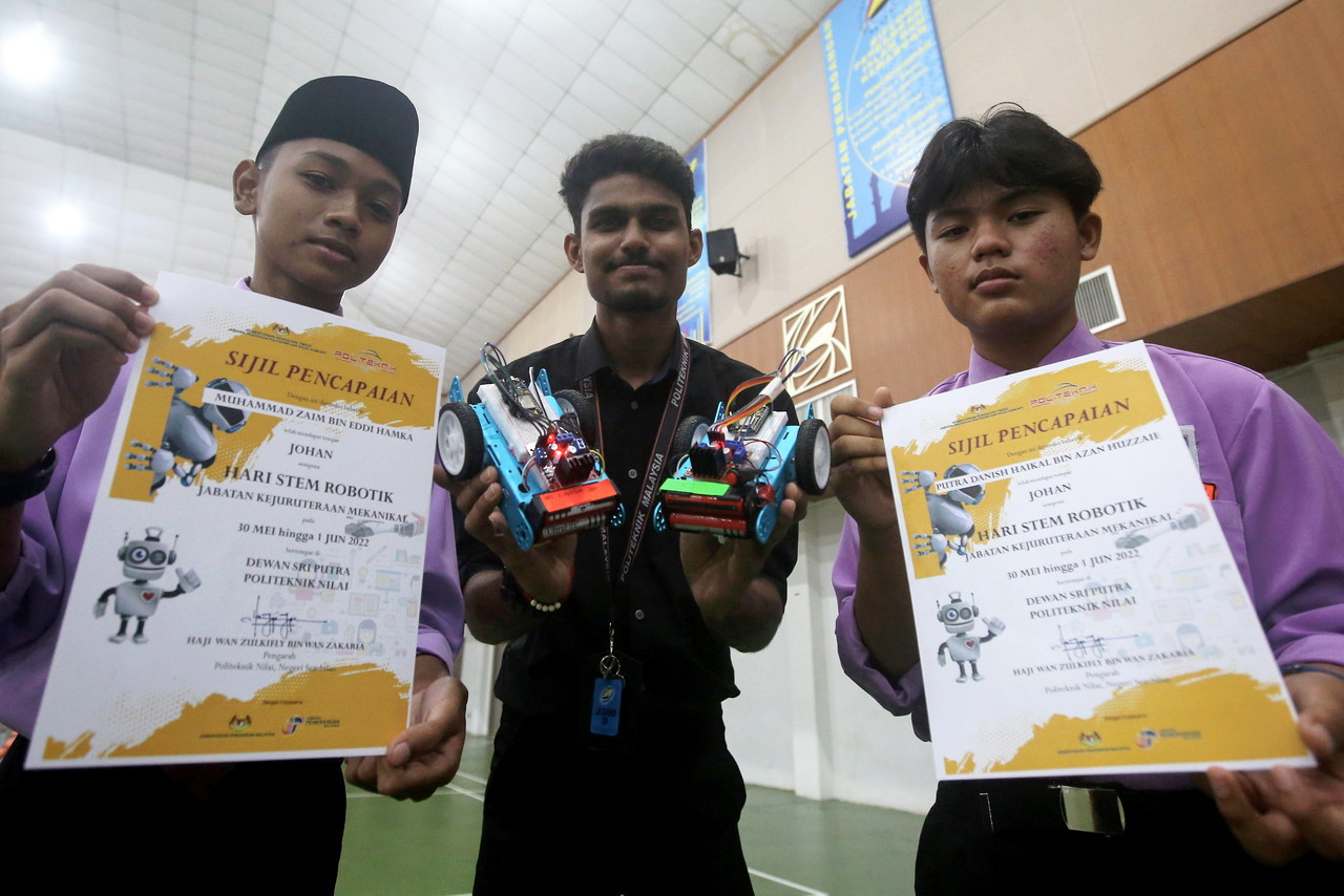 Putra Danish Haikal Azan Huzzaie (right) and Muhammad Zaim Eddi Hamka (left) made the most of the two-day learning session during the competition to learn about coding and robotics under the guidance of their facilitator S. Raxonraj (centre) from Nilai Polytechnic’s Diploma in Mechatronic Engineering programme. – Bernama pic, June 2, 2022