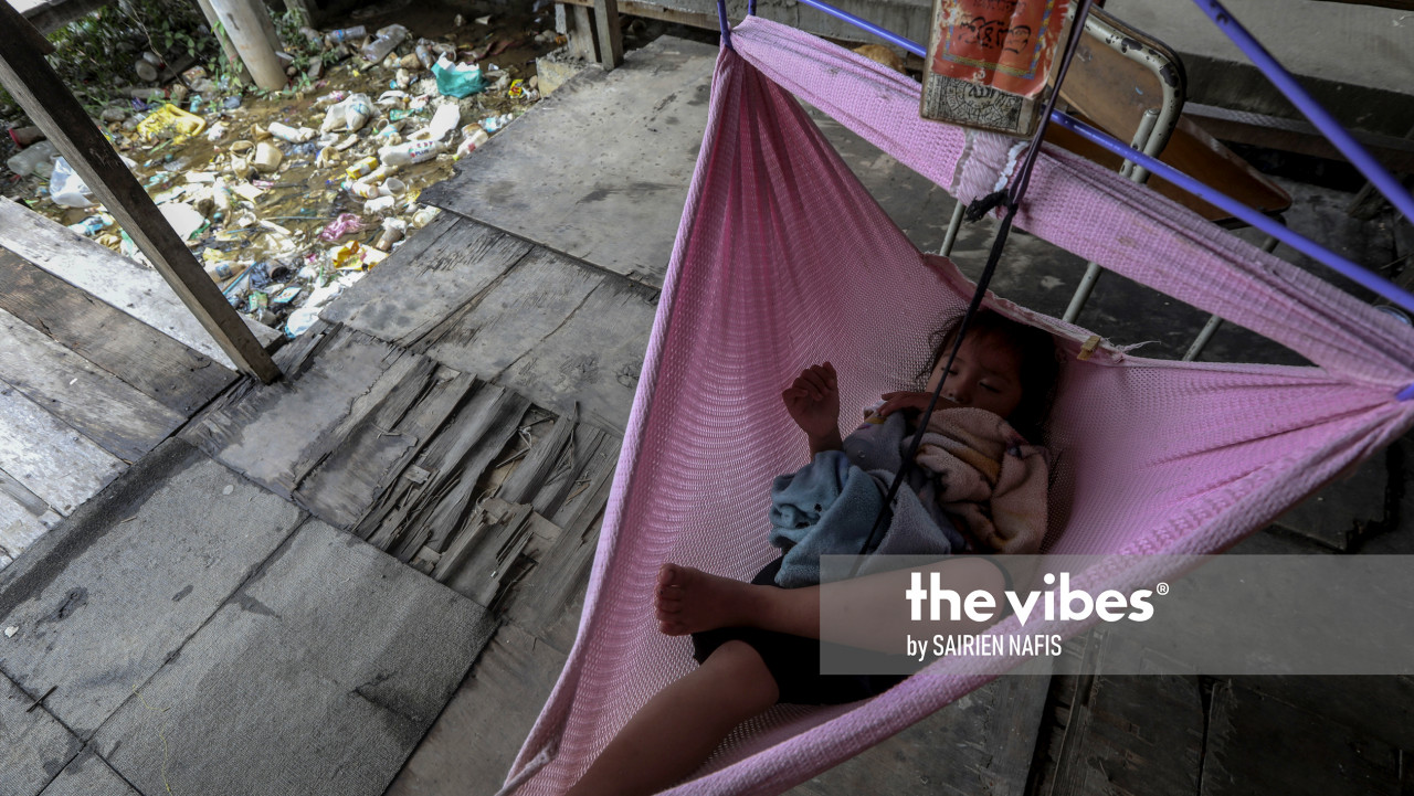 A toddler sleeps soundly in a cradle outside a house in Kg Numbak, where the water is choked with rubbish. – The Vibes pic, September 24, 2020