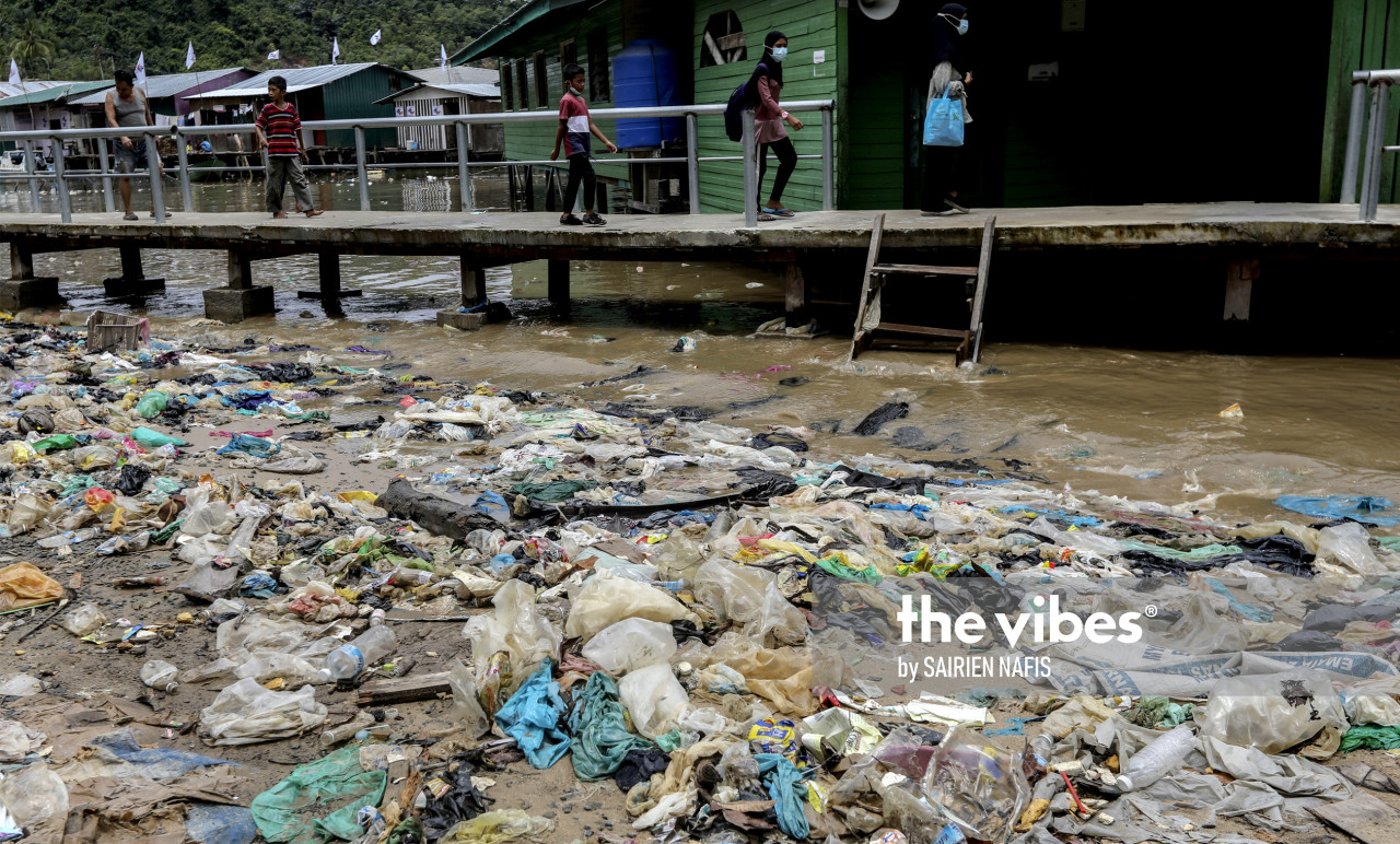 Residents walking towards their homes that are surrounded by garbage floating in the water. – The Vibes pic, September 24, 2020