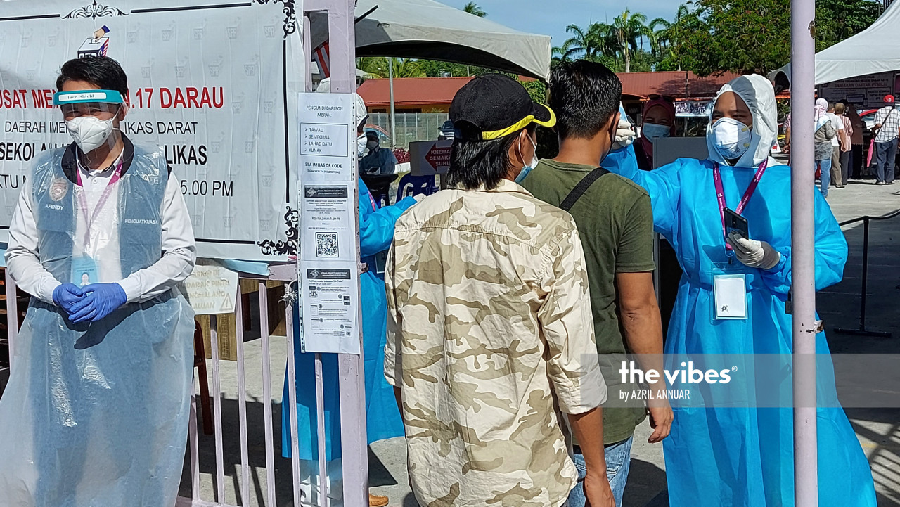 As part of the SOP amid the Covid-19 outbreak, Health Ministry officers are checking temperatures of those standing in line to vote in SMK Bahang, Kepayan. – The Vibes pic, September 26, 2020