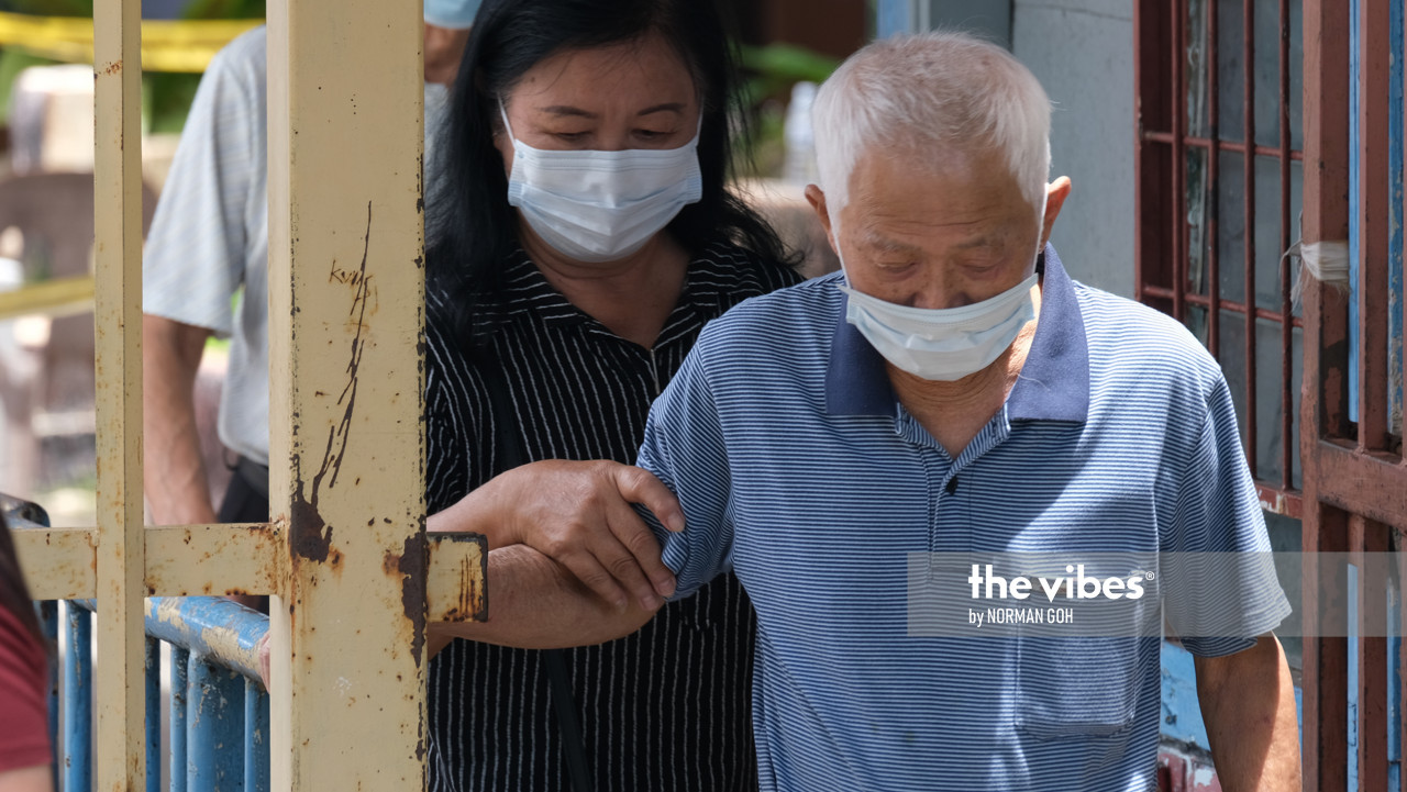 An old man is assisted by a family member at SMK Likas. – NORMAN GOH/The Vibes, September 26, 2020