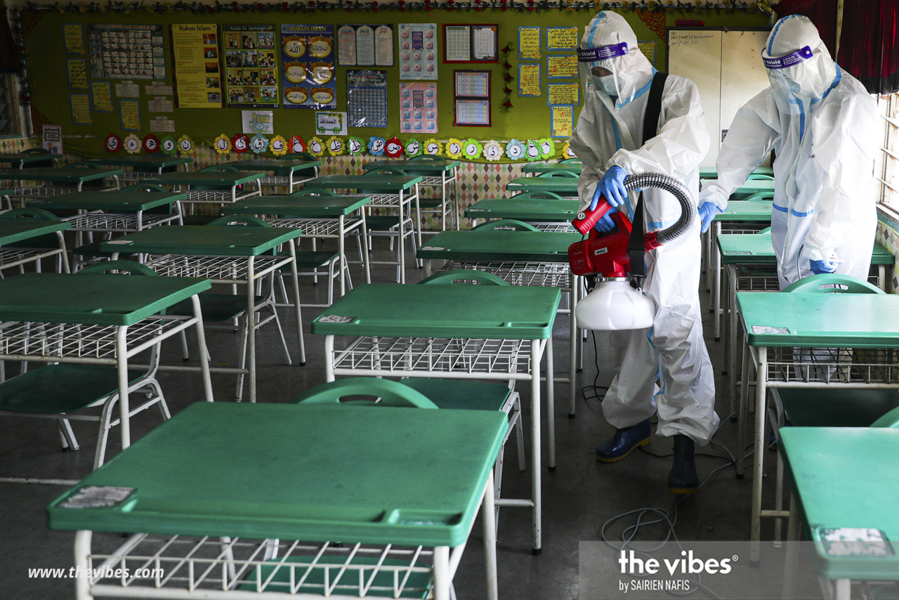 Two workers clad in PPEs disinfecting desks in a classroom at SRA Pandamaran Jaya in Klang, Selangor. – SAIRIEN NAFIS/The Vibes pic, February 28, 2021