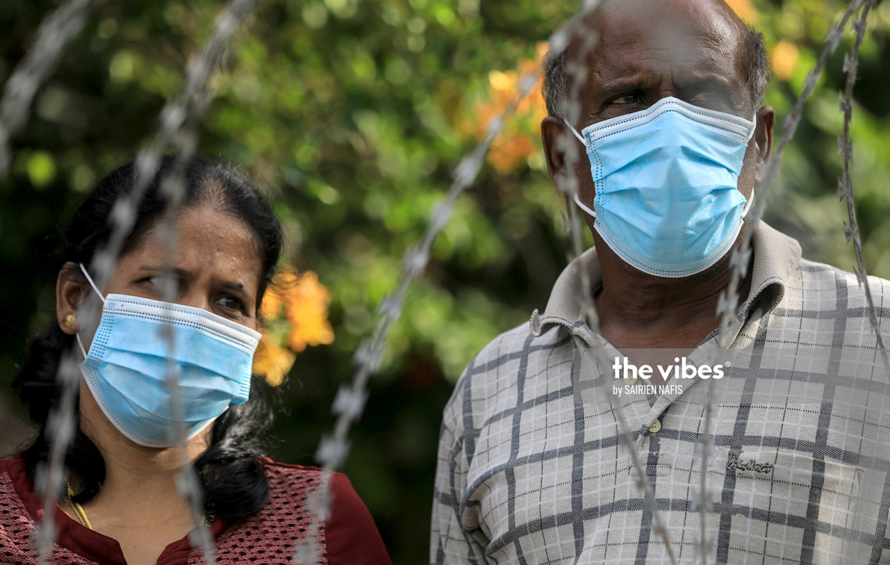 A couple stand near the barbed wire fencing which was put in place following the enforcement of the targeted movement control order in Sg Emas, on October 29, 2020. – SAIRIEN NAFIS/The Vibes, October 29, 2020