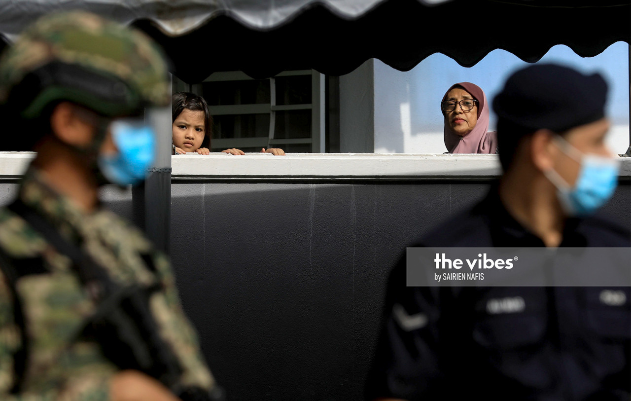 A curious kid looks out from her house at Sg Emas which has been placed under the targeted enhanced movement control order. – SAIRIEN NAFIS/The Vibes, October 29, 2020