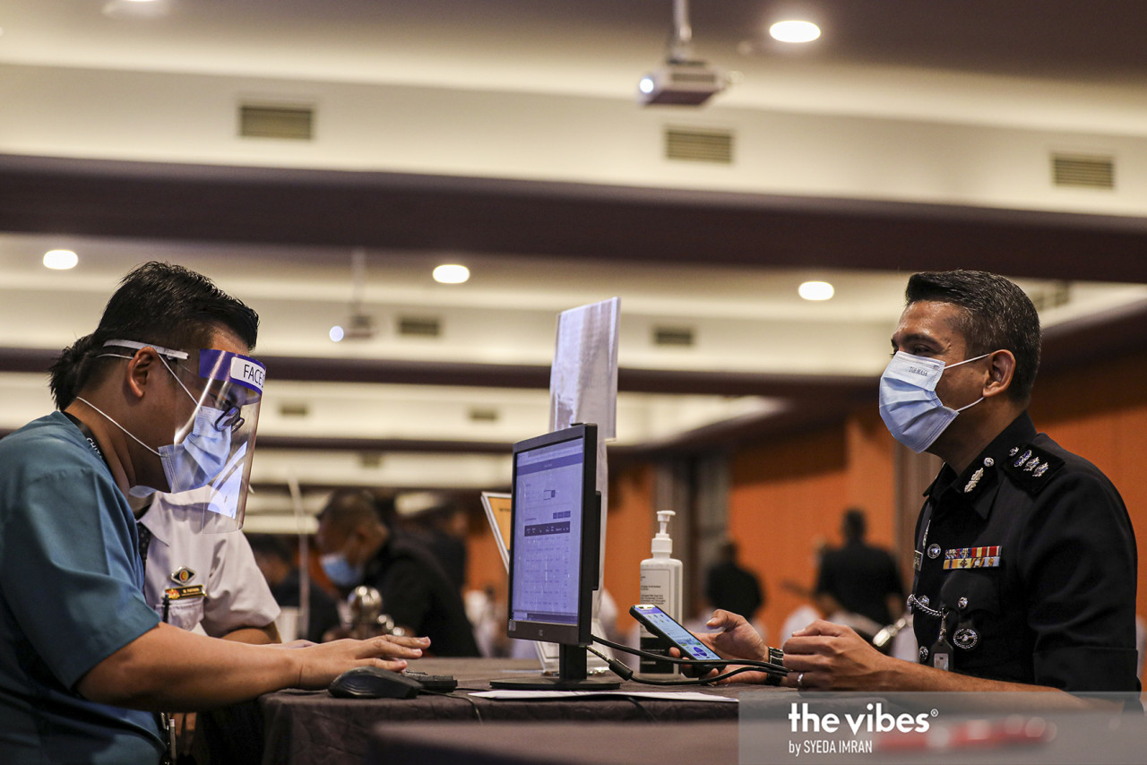 Petaling Jaya police chief Nik Ezanee Mohd Faisal is all smiles behind his mask as he registers for the coronavirus vaccination. – SYEDA IMRAN/The Vibes pic, March 10, 2021