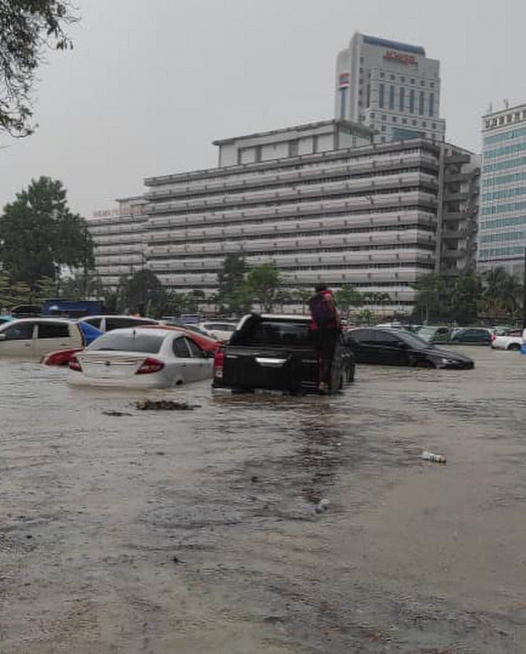 A man stands on top of his submerged vehicle in Johor Baru during today’s flood. – @bencanamalaysia Twitter pic, August 2, 2022