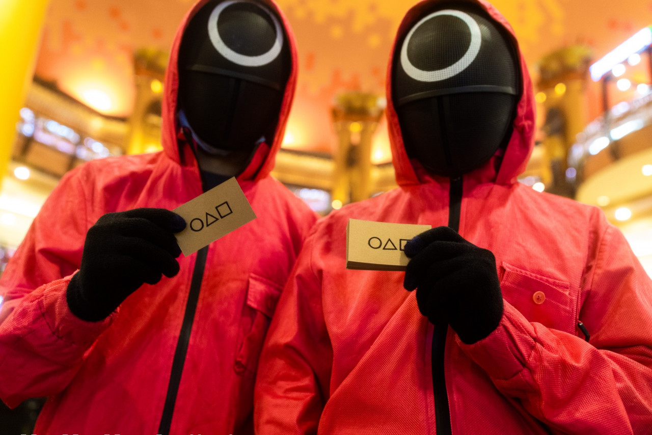 Get a business card from a bemasked man. – Netflix pic