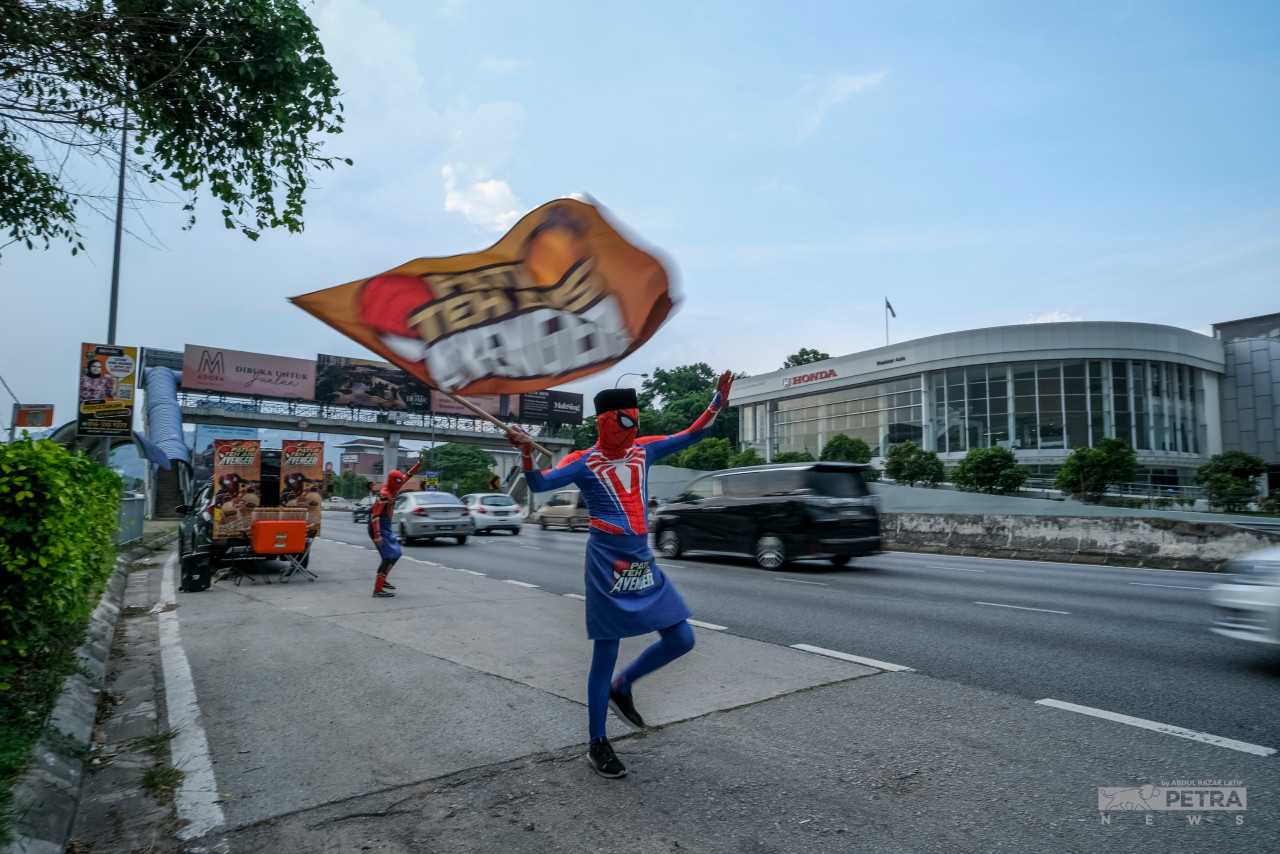 Various methods were used by Mohamed Zakri Mohd Sofi assisted by Mohd Shafiqal Azrin Mohd Azmi to attract the attention of MRR2 road users. – ABD RAZAK LATIF/The Vibes pic, April 27, 2022