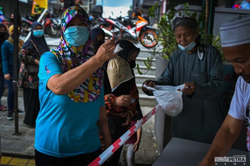 A woman showing the bubur lambuk received from volunteers from the Kampung Baru Jamek Mosque. – SYEDA IMRAN/Getaran pic