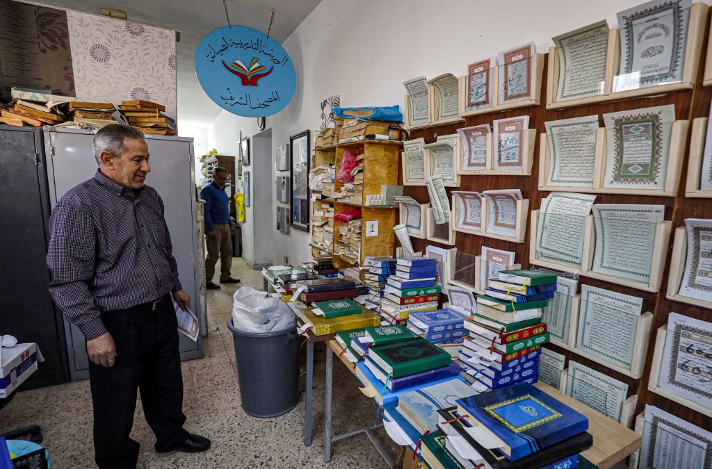Khaled al-Drebi, renowned Libyan restorer of the Quran, standing before restored volumes during a workshop on the restoration of Quran copies in Tripoli on March 22, 2022. – AFP pic
