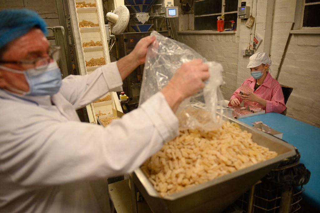 A member of staff at the traditional sweet manufacturer Edward Grays of Dudley, or better known locally as 'Teddy Grays', places freshly-made Grays Herbal Tablets onto a hopper to be automatically bagged in their factory in Dudley, central England on January 25, 2022. – AFP pic