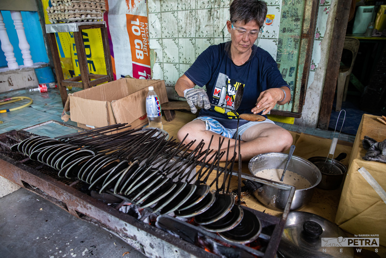 Lee Chau Te, 63, arranging dozens of kuih kapit moulds on a charcoal stove. – SAIRIEN NAFIS/The Vibes pic, January 31, 2022 