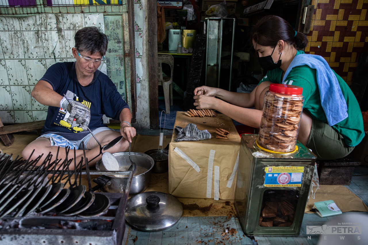 Lee Chau Te, with the help of his daughter, Annie Lim, makes kuih kapit, some of which are ordered by the locals of Pulau Ketam and the surrounding areas. – SAIRIEN NAFIS/The Vibes pic, January 31, 2022