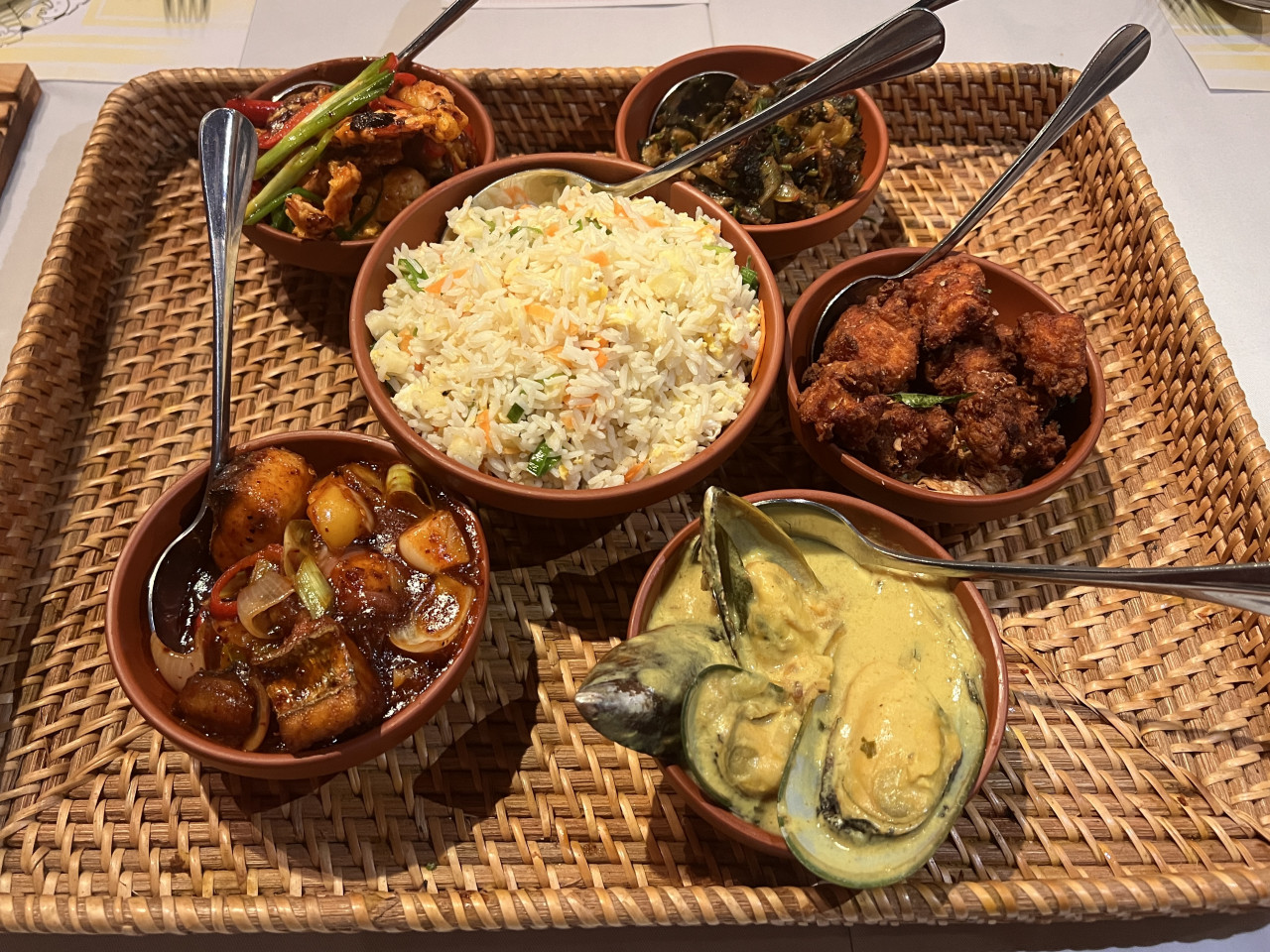  (Clockwise from upper left) Batter fried prawns, pucuk paku with tempered mushrooms, pepper chicken, mussel curry, and devilled fish. The pineapple rice sits in the middle. It should be enough for a hungry couple or maybe more. – Haikal Fernandez pic