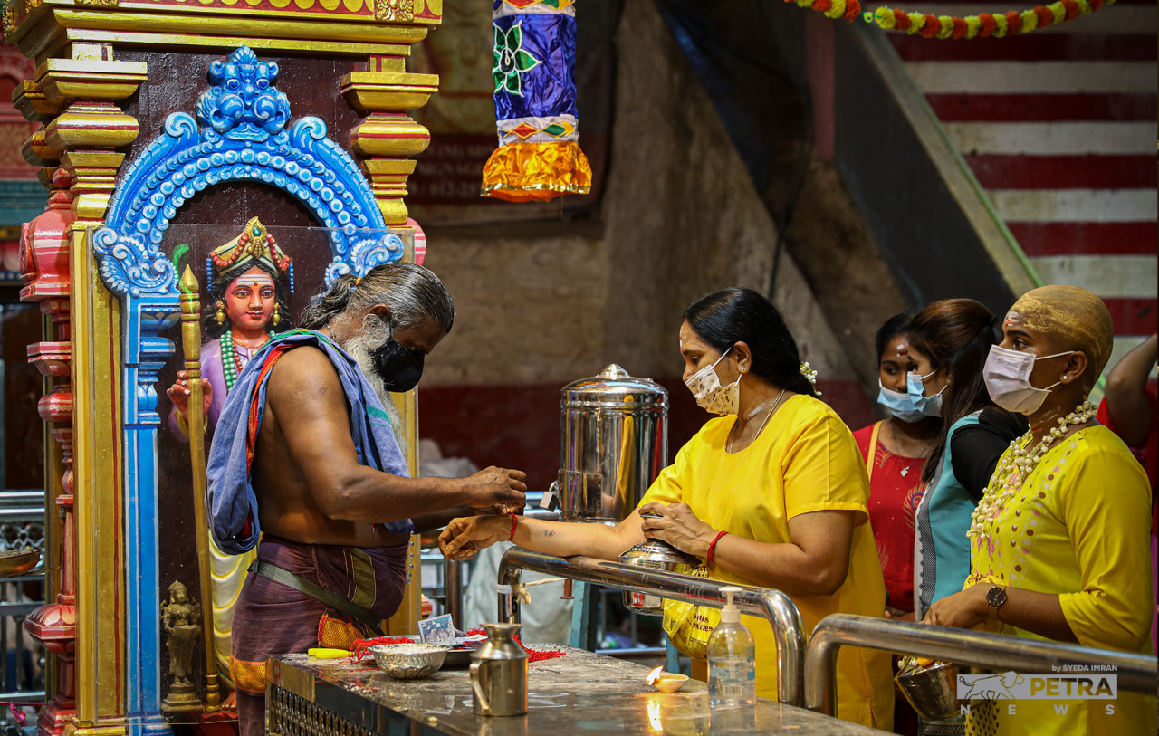 A priest ties a sacred bracelet around a paal kudam-bearer's wrist to mark the end of her Thaipusam journey. – SYEDA IMRAN/The Vibes pic, January 18, 2022