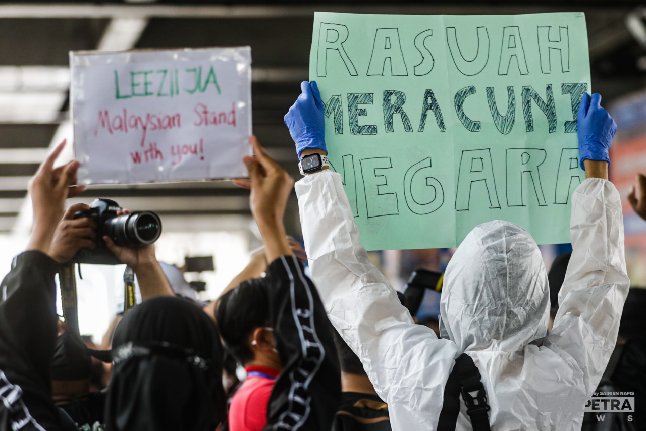‘Corruption poisons the country’, reads one of the placards held by a protestor (right) with another in support of Lee Zii Jia, Malaysia national shuttler who was dropped from international competitions by the Badminton Associations of Malaysia. – SAIRIEN NAFIS/The Vibes pic, January 23, 2022