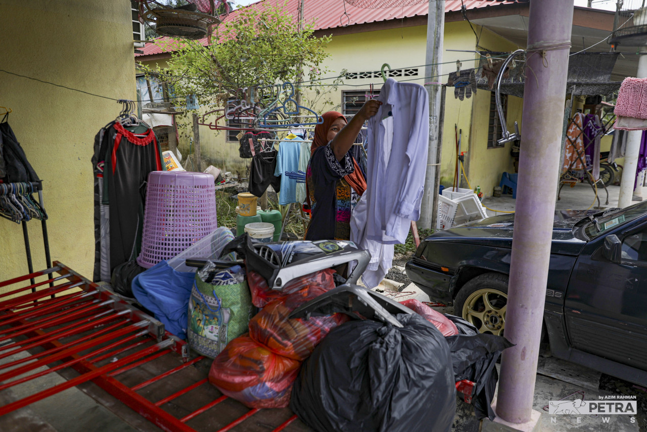 Siti Nurkhadijah Hasih hangs her son’s school uniform to dry in preparation for the reopening of schools. – AZIM RAHMAN/The Vibes pic, January 17, 2022