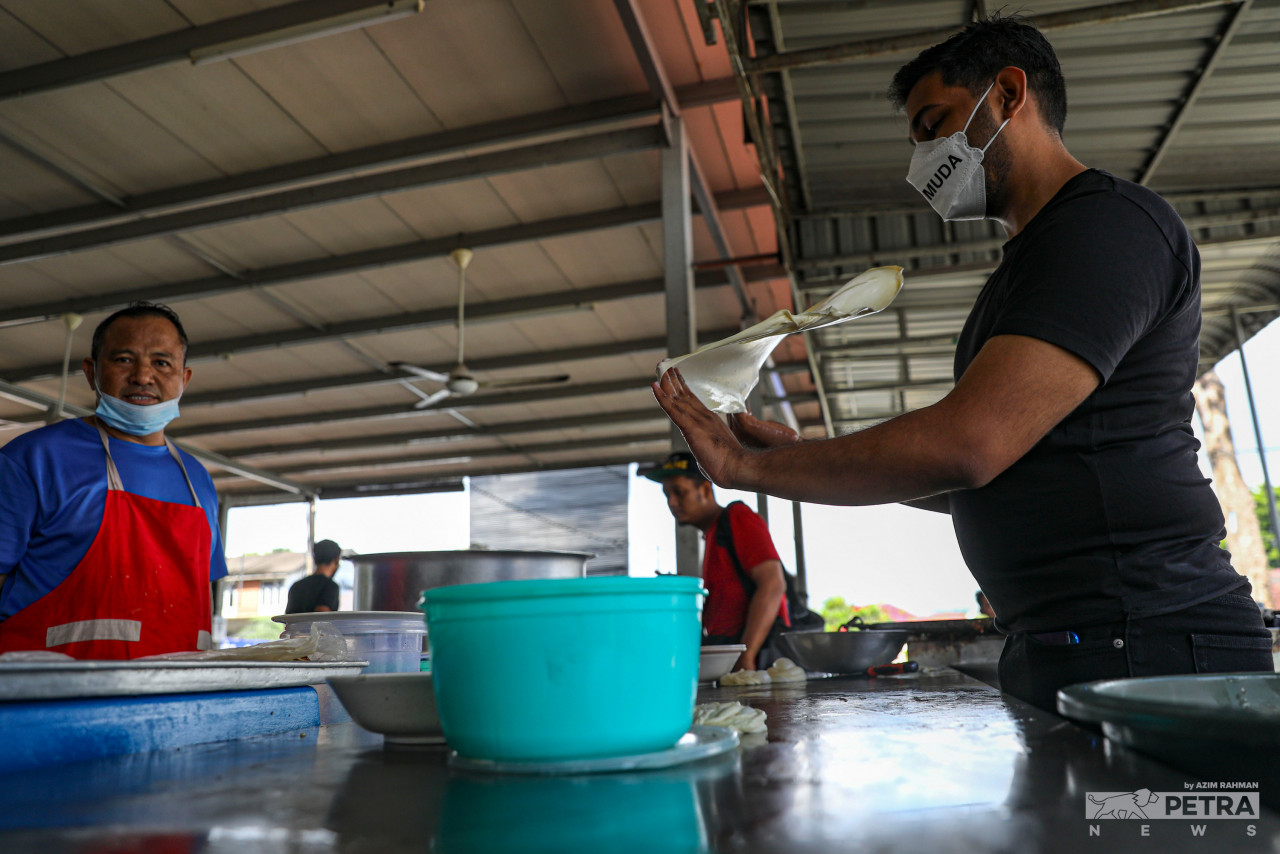 Muda candidate for the Larkin state seat, Rasid Abu Bakar shows his talent in making roti canai while campaigning at the Man Tebar Larkin food stall. – AZIM RAHMAN/The Vibes pic, March 10, 2022 