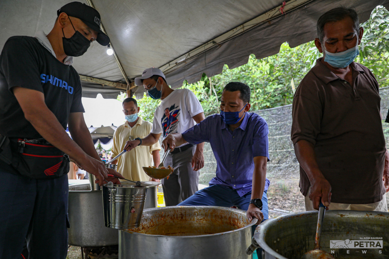 Despite competing in different political parties, Barisan Nasional candidate for the Pemanis state seat, Anuar Manap (second from right) with his political rival from Perikatan Nasional, Uzair Ismail (third from left) scoop side dishes together with the villagers at a wedding ceremony in Kampung Jawa, Segamat. – AZIM RAHMAN/The Vibes pic, March 10, 2022 
