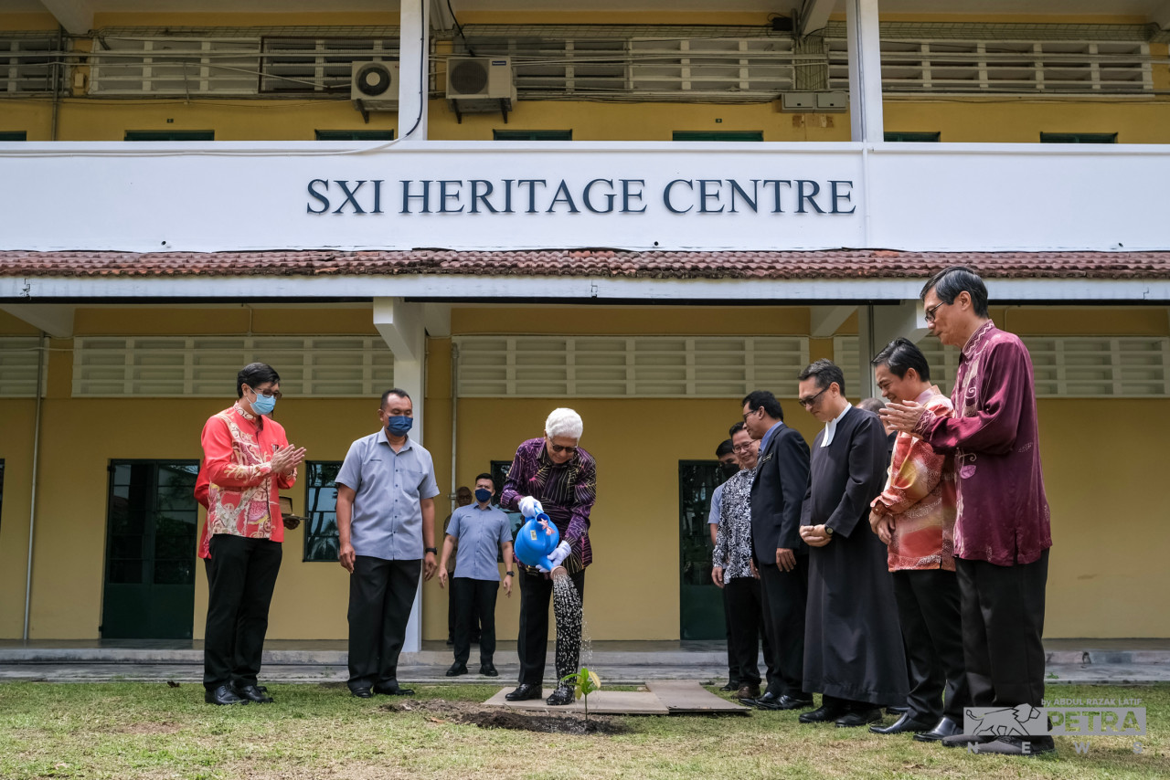 Ahmad Fuzi (centre) watering a tree sapling. Looking on are the SXI Heritage Gallery committee. – ABDUL RAZAK LATIF/The Vibes pic