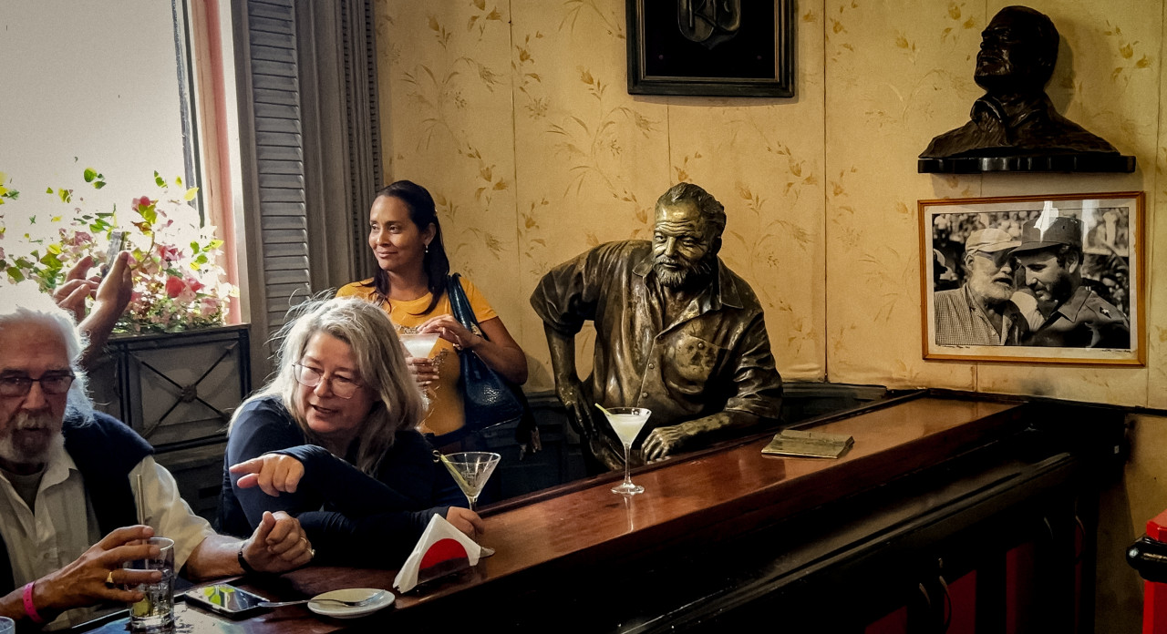 Tourists drink cocktails next to a sculpture of US novelist Ernest Hemingway at the Floridita bar in Havana on December 27, 2022. – AFP pic