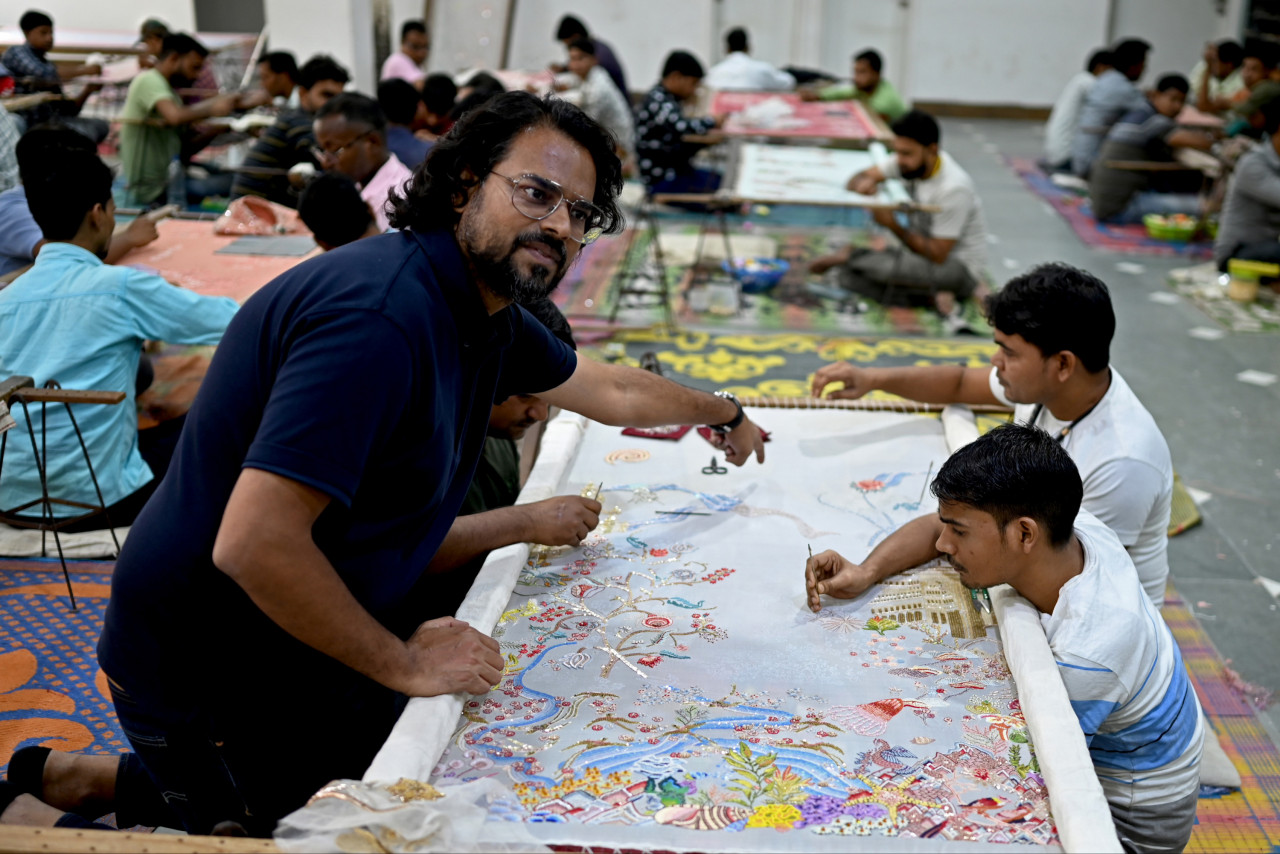 Mishra (left) sits with the men working on his designs at a workshop in Noida on October 19, 2022. – AFP pic