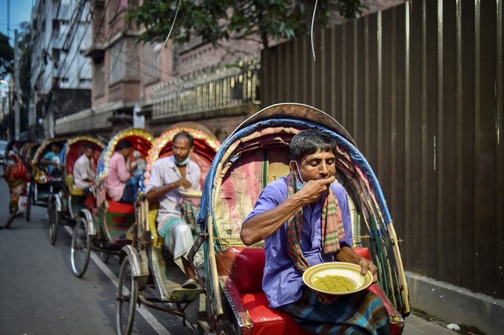 Pandemic affected people eating food distributed by Mehmankhana on July 26. – AFP pic