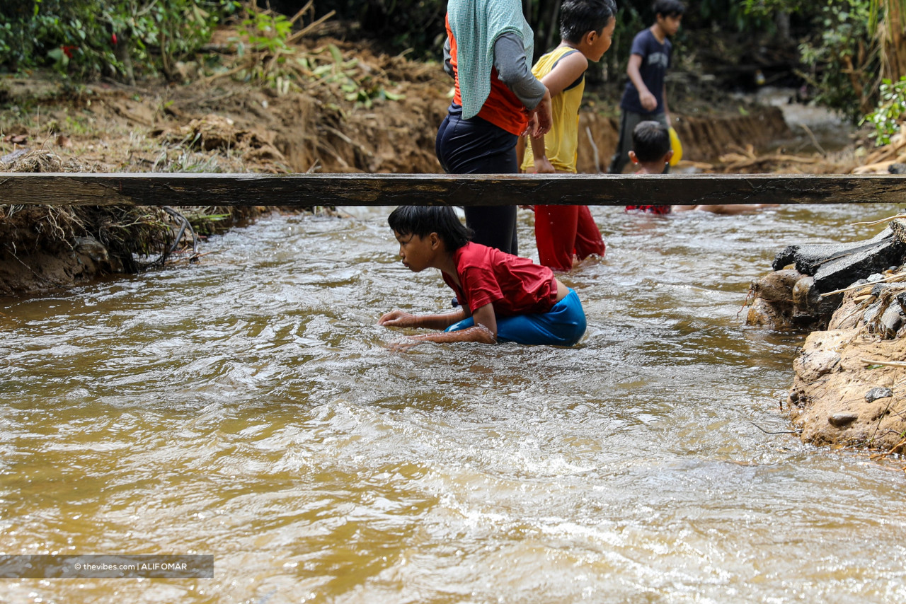 Children playing in a ‘river’ that formed near Marzuki Othman’s home following flooding last week. – ALIF OMAR/The Vibes pic, August 25, 2021