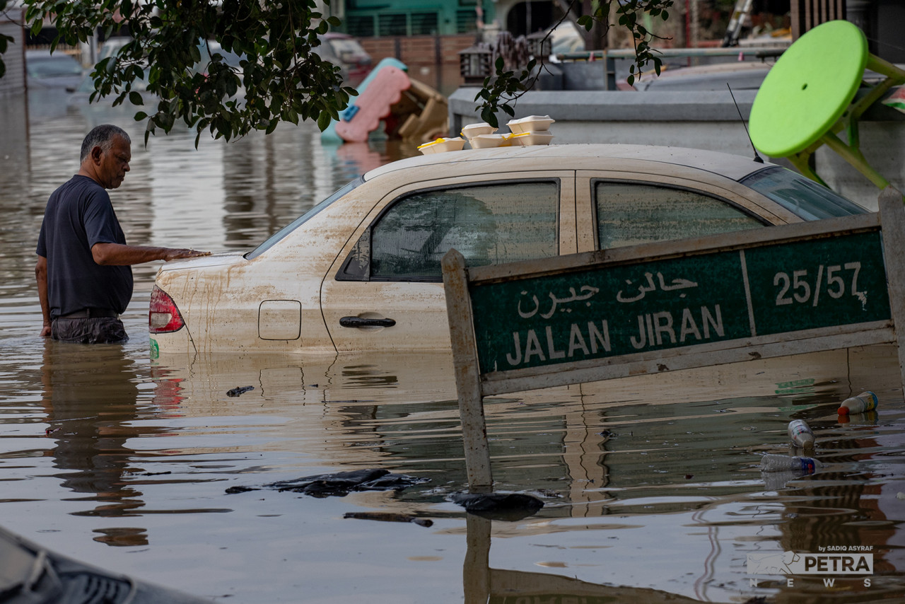 A resident inspects the condition of his car that was submerged in the massive Taman Sri Muda flood. – SADIQ ASYRAF/The Vibes pic, December 22, 2021