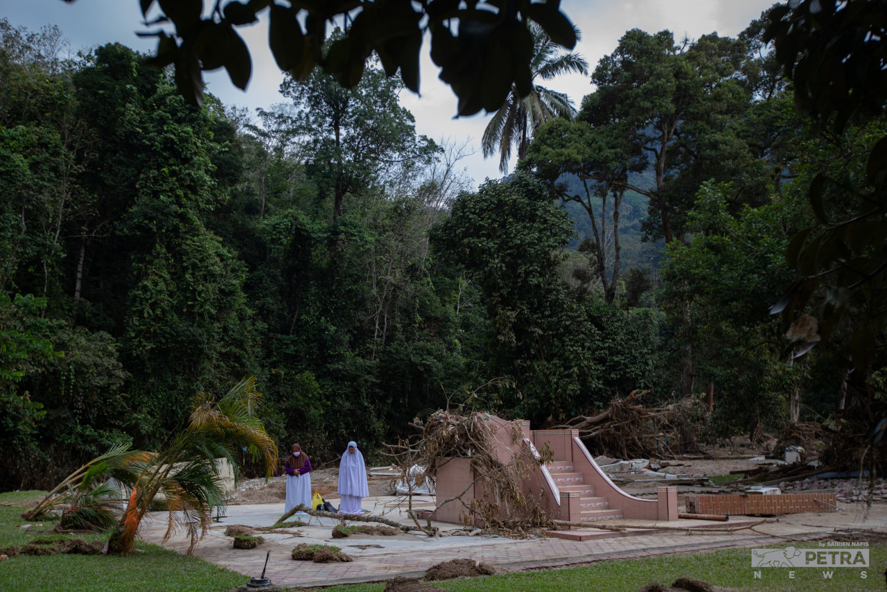 Flood victim Rohana Mahfuz (left) performing her prayers at the remains of her family house in Hulu Langat, which was washed away by the recent floods. – SARIEN NAFIS/The Vibes file pic, December 31, 2021