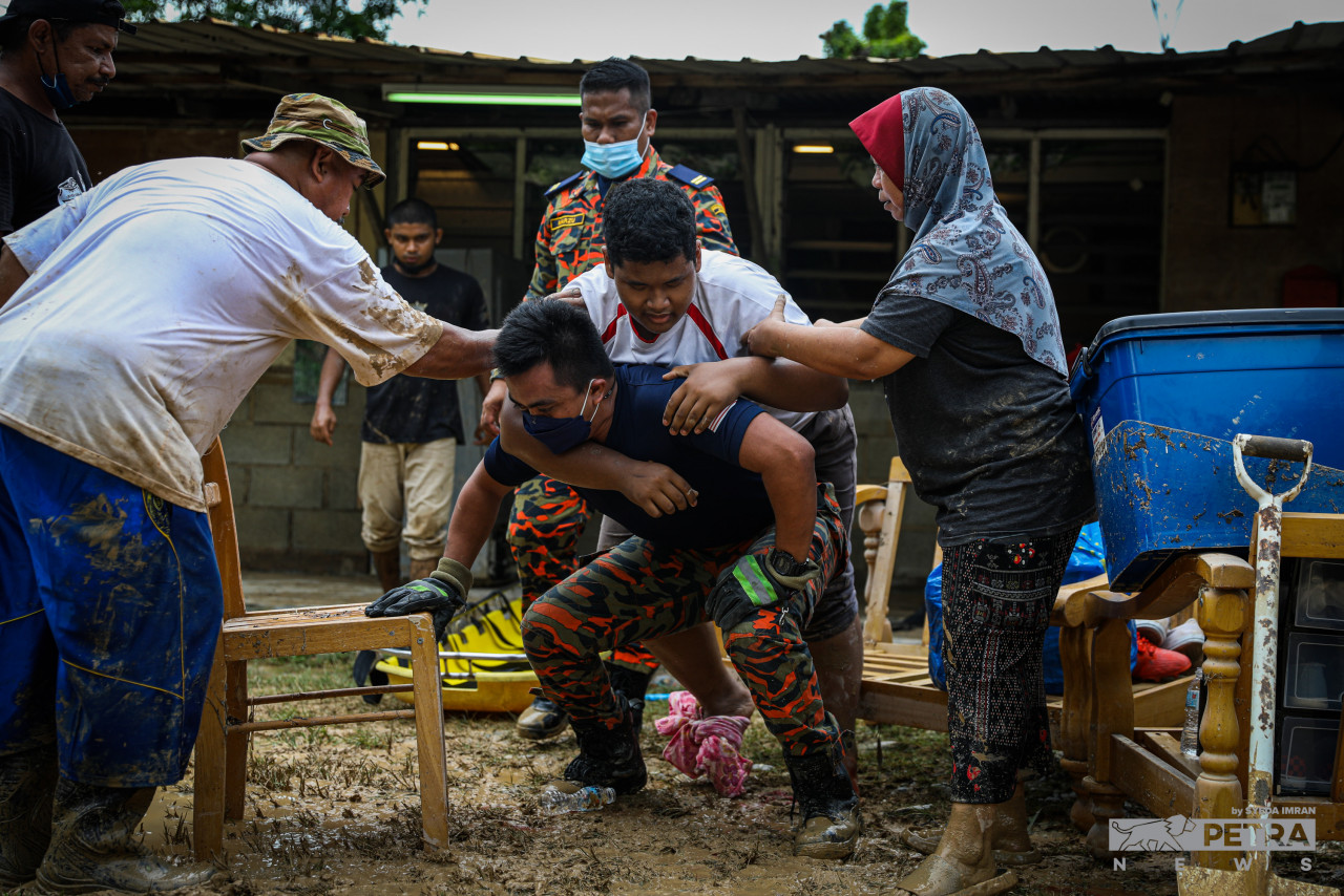 A Fire and Rescue Department officer helping to extricate a good Samaritan who had stepped on glass embedded in mud, following flash floods in Ampang on November 25, 2021. – SYEDA IMRAN/The Vibes file pic, December 31, 2021 
