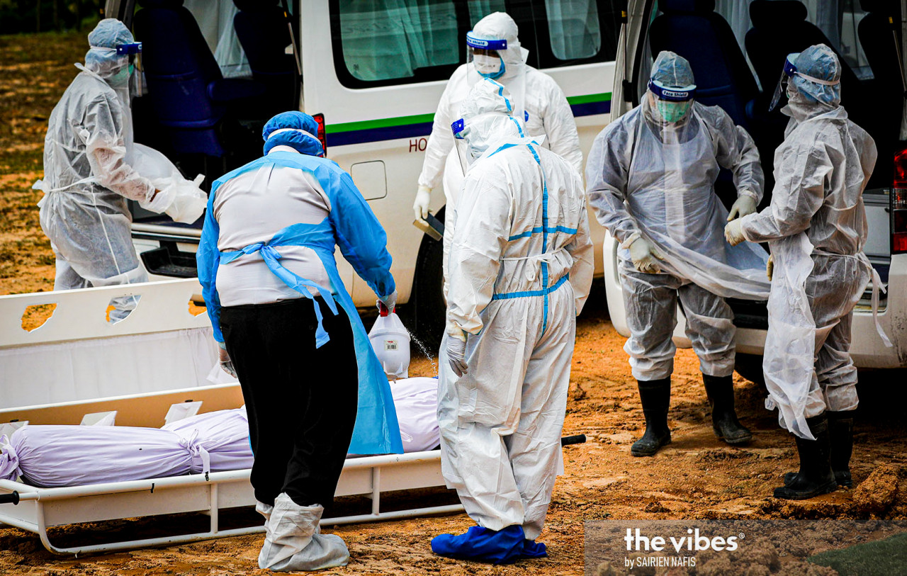 Disinfectant is sprayed on the shrouded remains of a Covid-19 victim at the Kota Damansara Muslim cemetery. – The Vibes pic, February 4, 2021