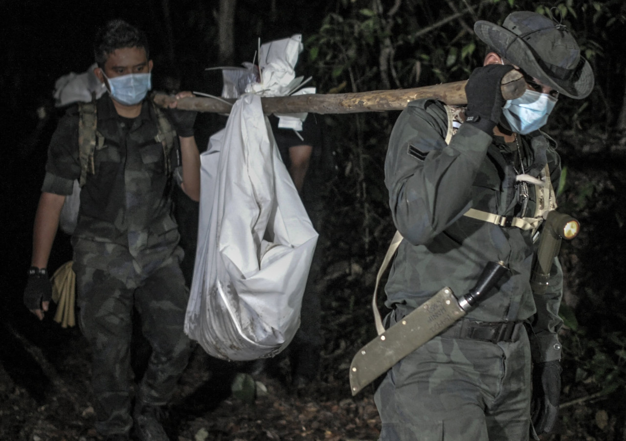 Malaysian police personnel carry exhumed human remains recovered from the jungle in Wang Kelian, Perlis on May 28, 2015. Three days earlier, police had announced the discovery of 139 graves and 28 suspected human-trafficking camps in the area, just over the border from Thailand. – AFP pic, October 18, 2022
