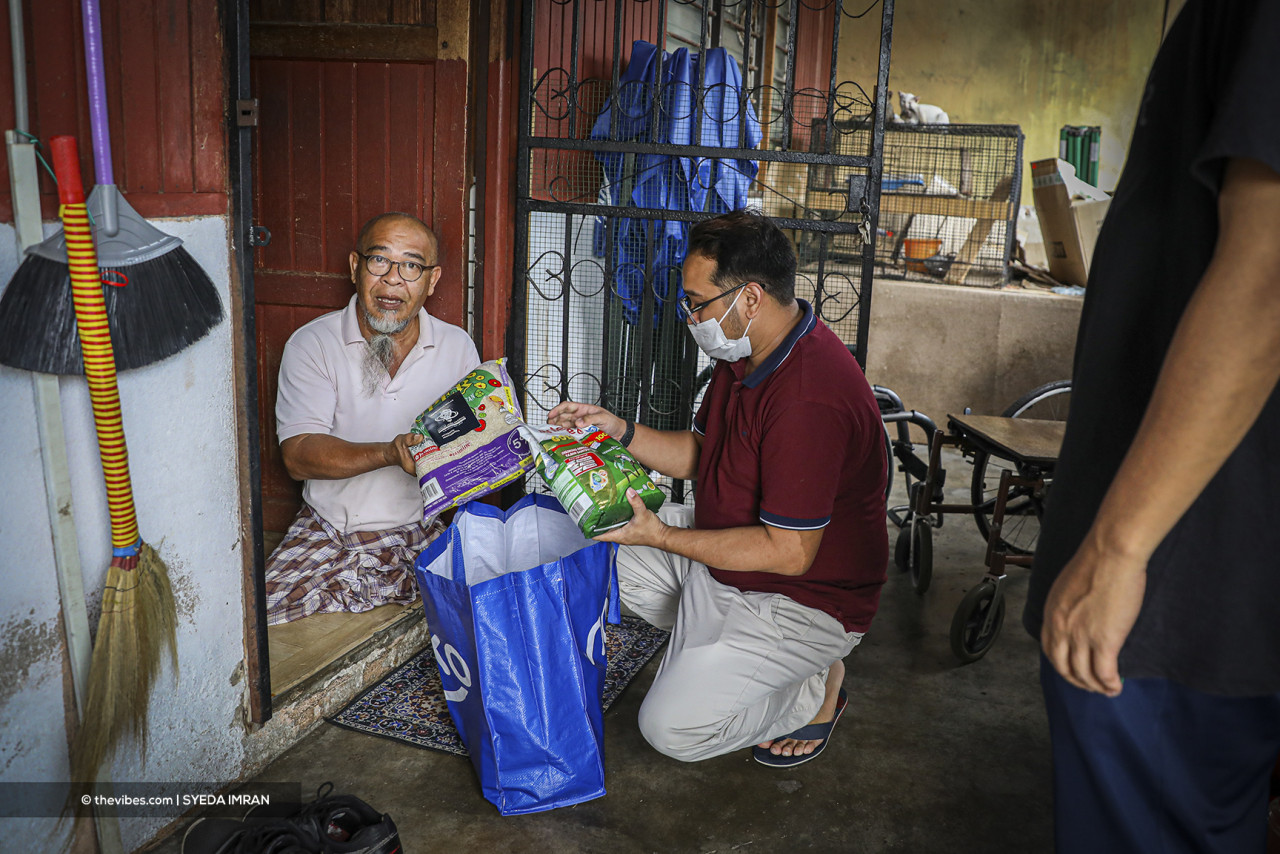 Representatives from NGO Intelek Musa Nasional hand out essential foodstuffs to a man in need of help. – SYEDA IMRAN/ The Vibes pic