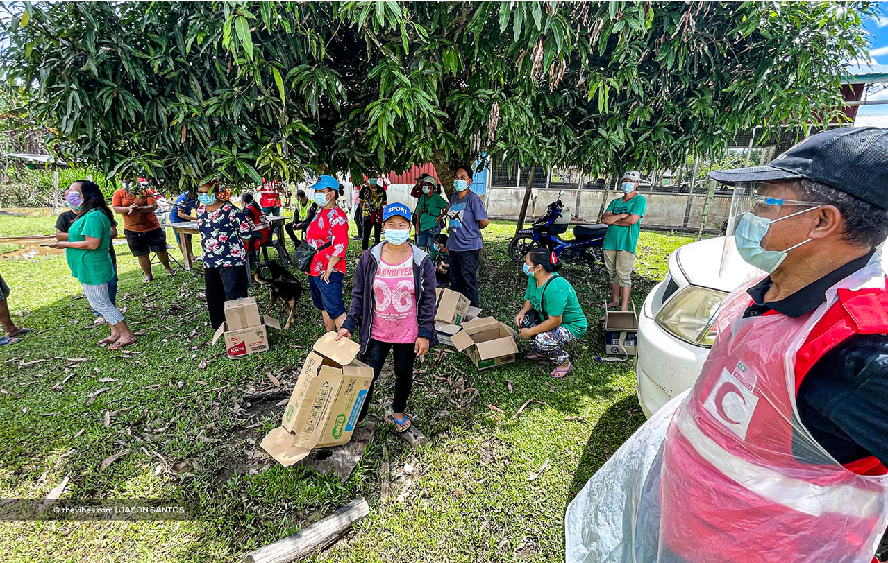 Gimbang talking to recipients who are waiting to get their food aid from Women of Will (WoW) distributed by the Red Crescent in a Sook village, in Keningau. – JASON SANTOS/The Vibes pic