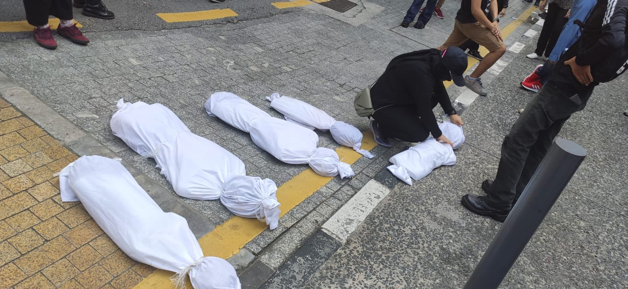 Mock corpses symbolising Covid-19 victims are arranged on the ground. – The Vibes pic, July 31, 2021