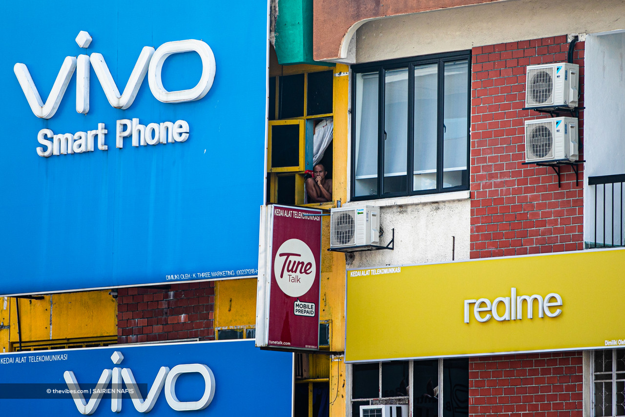A tenant of a unit above a mobile phone shop looks out the window on the first day of the total lockdown. – SAIRIEN NAFIS/The Vibes pic, June 1, 2021