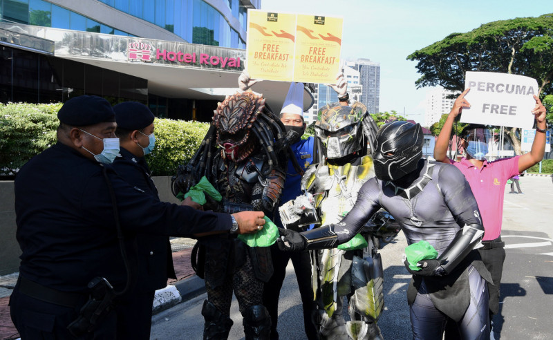 Three costumed heroes distribute free food in Penang