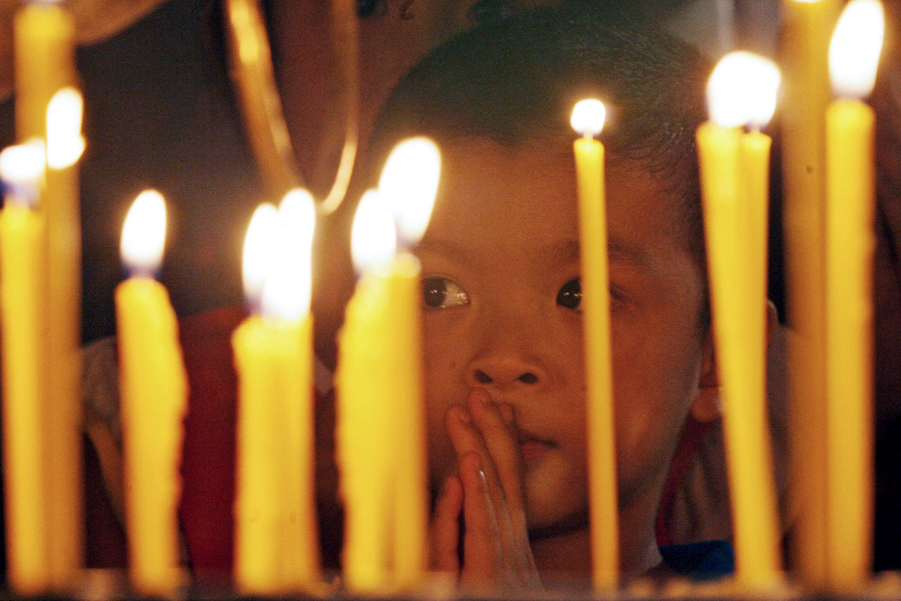 A child is seen praying behind lit candles during one of the holiest dates in the Buddhist calendar. Picture taken during Wesak celebrations in 2007. – AFP pic