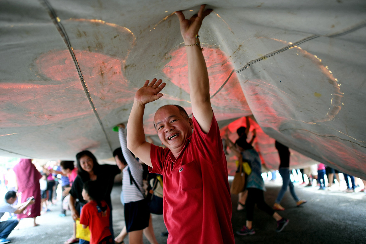Buddhist devotees walk under an over two decades old 196-foot-long sacred 'Thangka' during the Buddha Day festival celebrations at the Enlightened Heart Tibetan Buddhist temple in Ipoh on May 10, 2017. – AFP pic